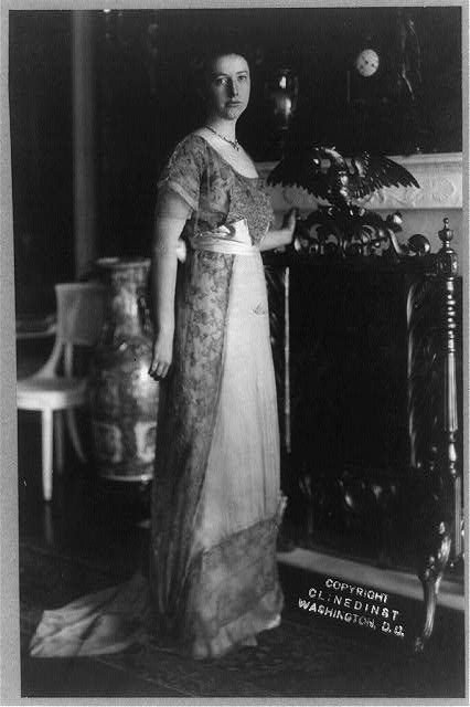 Helen Taft, full-length portrait, standing by fireplace, facing right