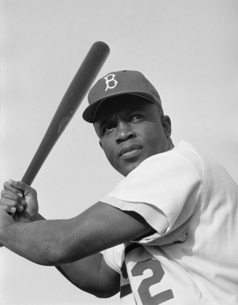 Jackie Robinson wearing his number 42 jersey holding a baseball bat.