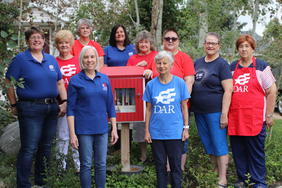 DAR members stand by a little free library they built as part of a community service effort.