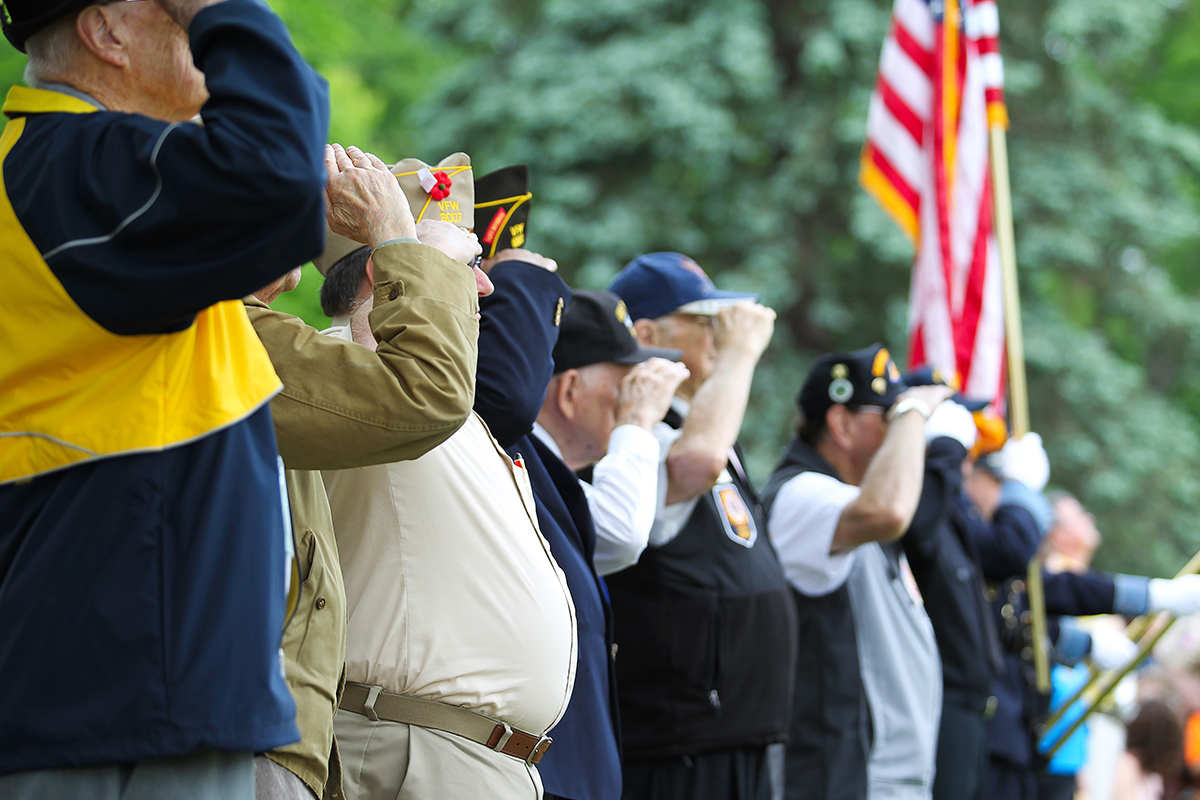 Veterans salute during a patriotic event honoring service and community sacrifice.
