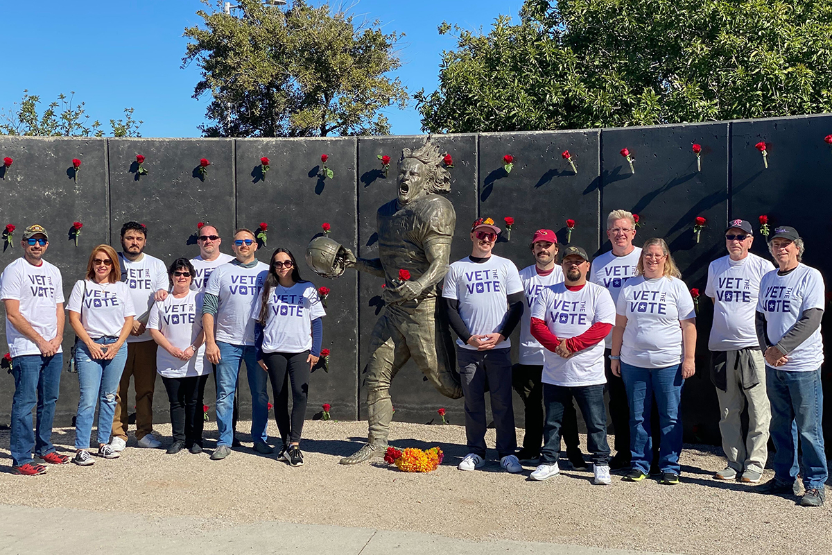 Veterans and volunteers stand united at a memorial, promoting civic engagement and service.
