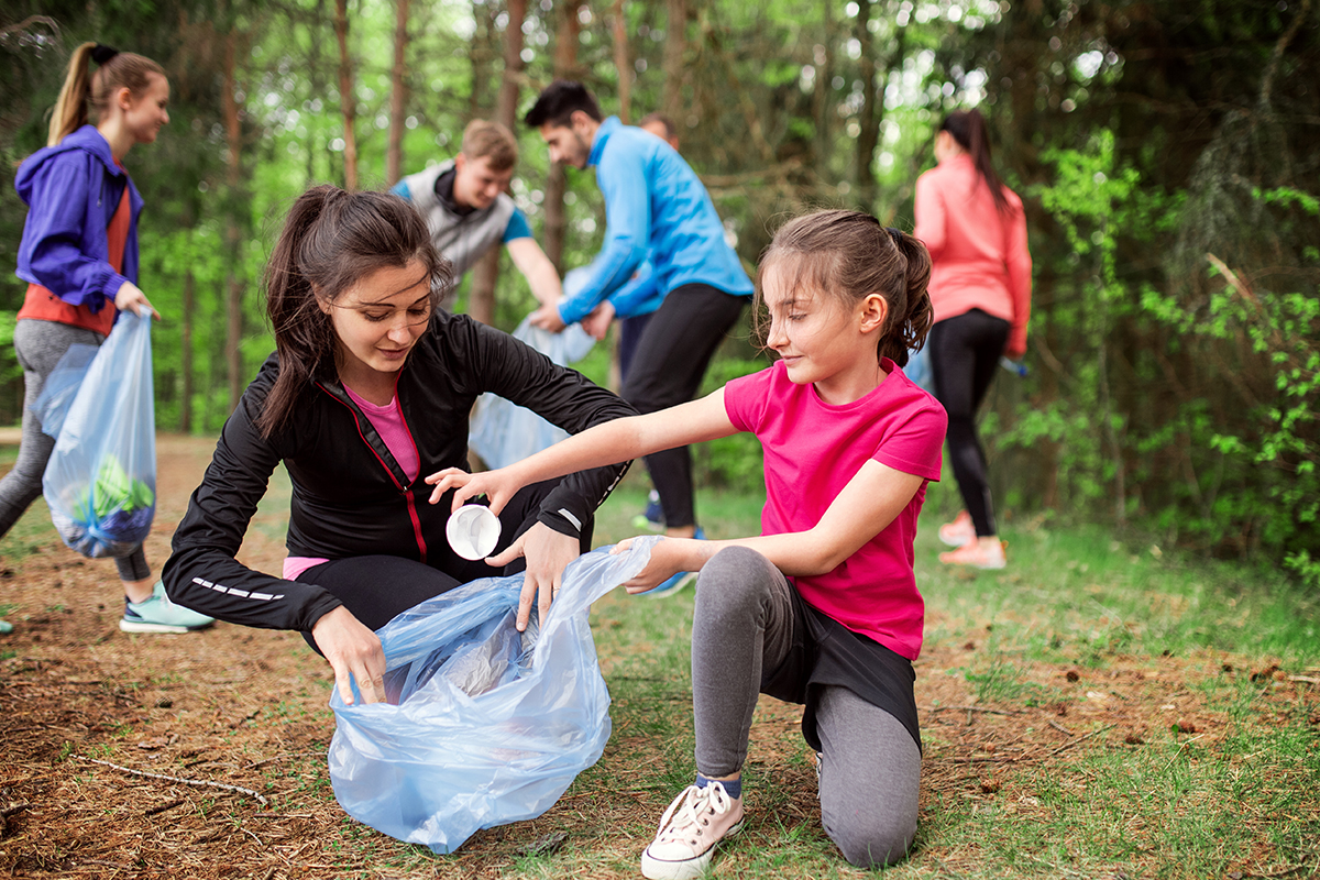 Young volunteers clean up a park, collecting litter to support environmental service efforts.