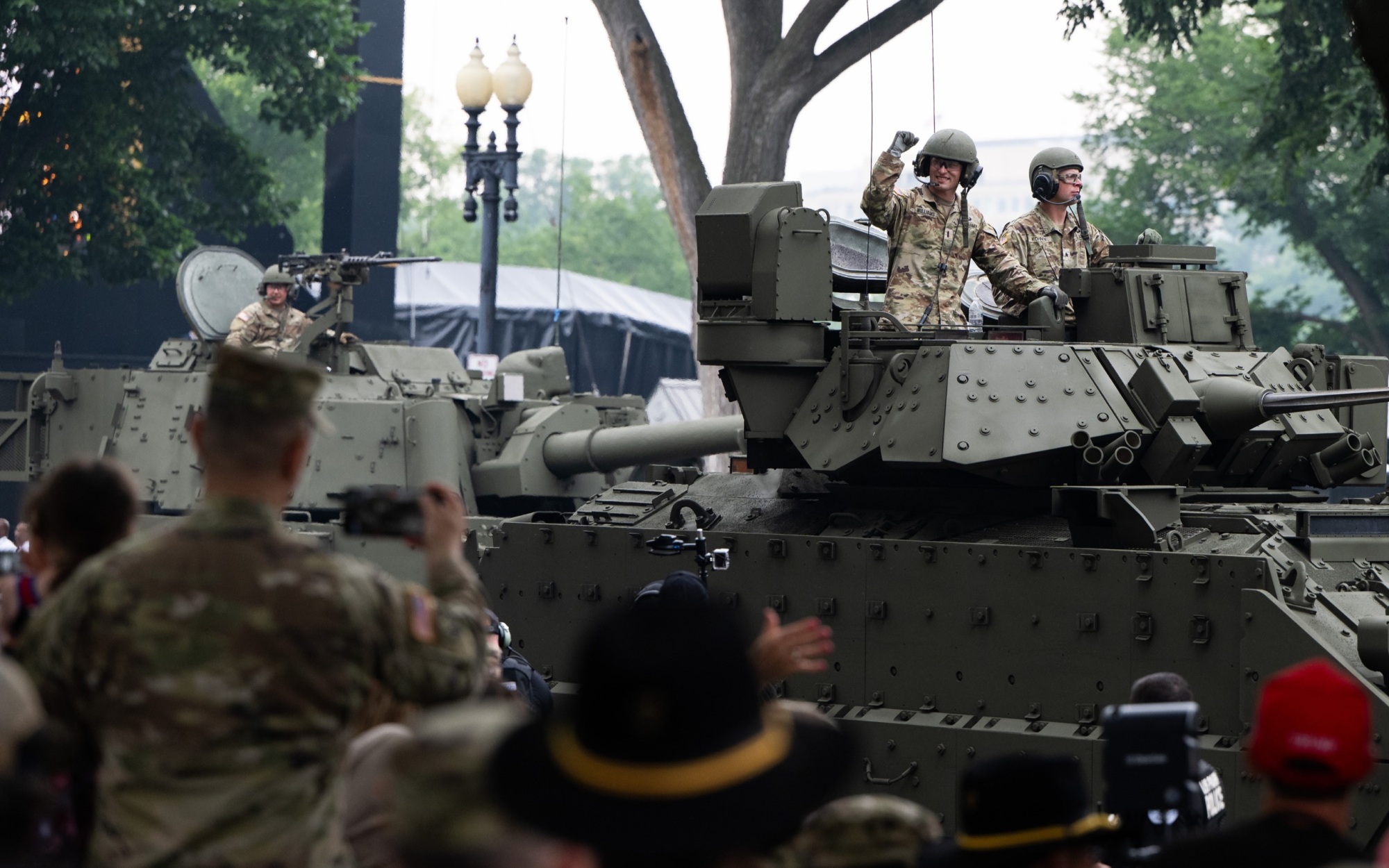 Soldier raising his arm while riding on parade in a Bradley Fighting Vehicle