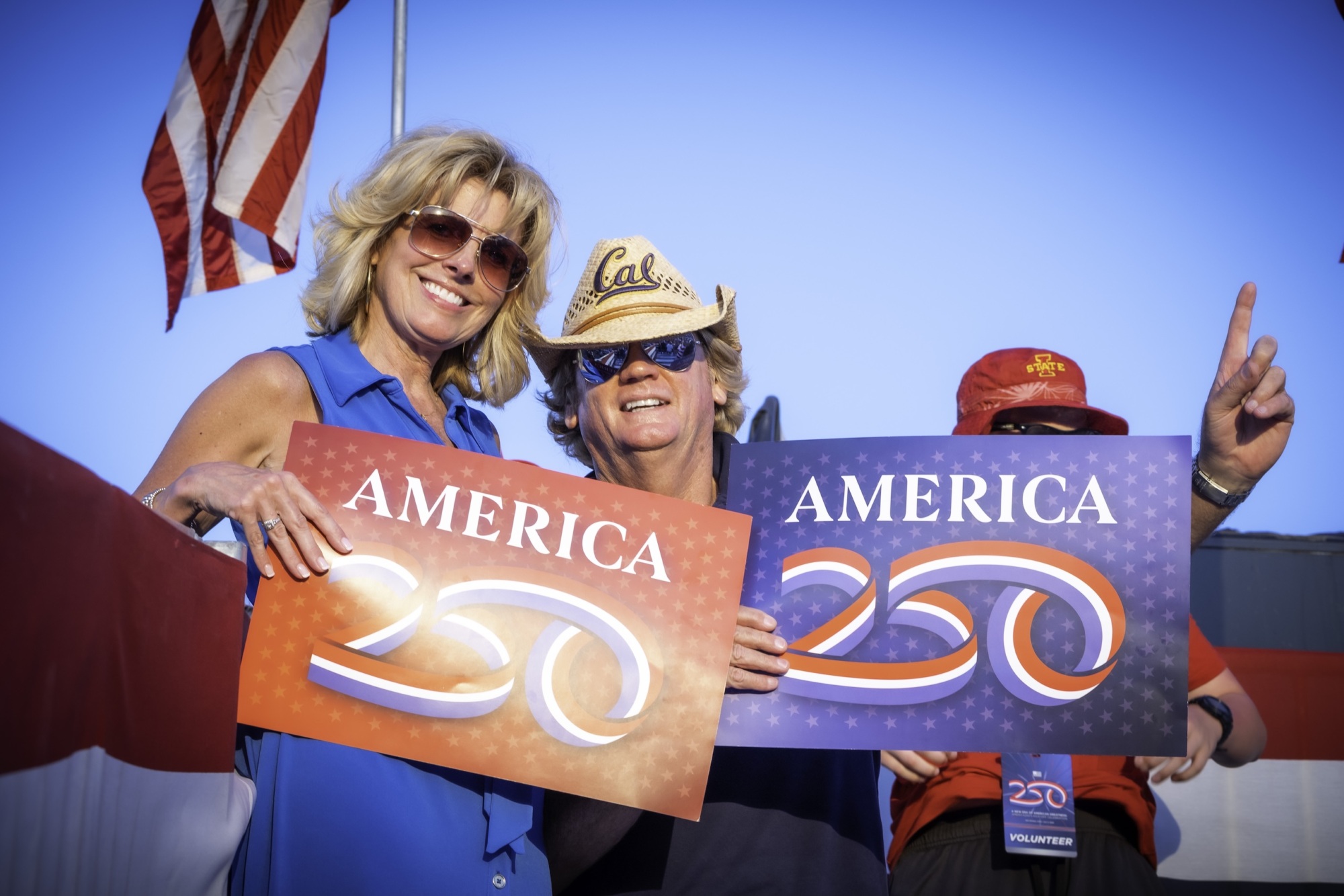 Man and woman with America250 signs at Iowa event on July 3 2025