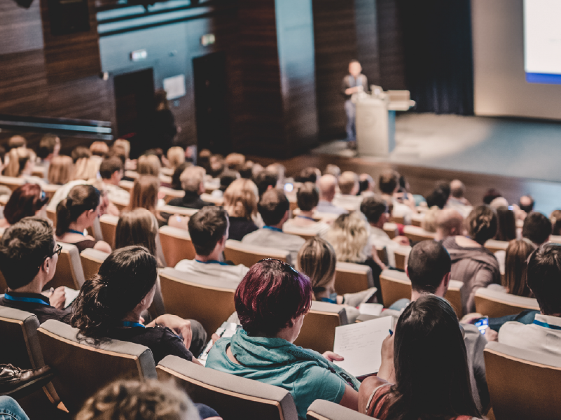 Lecture hall with full audience and speaker at podium